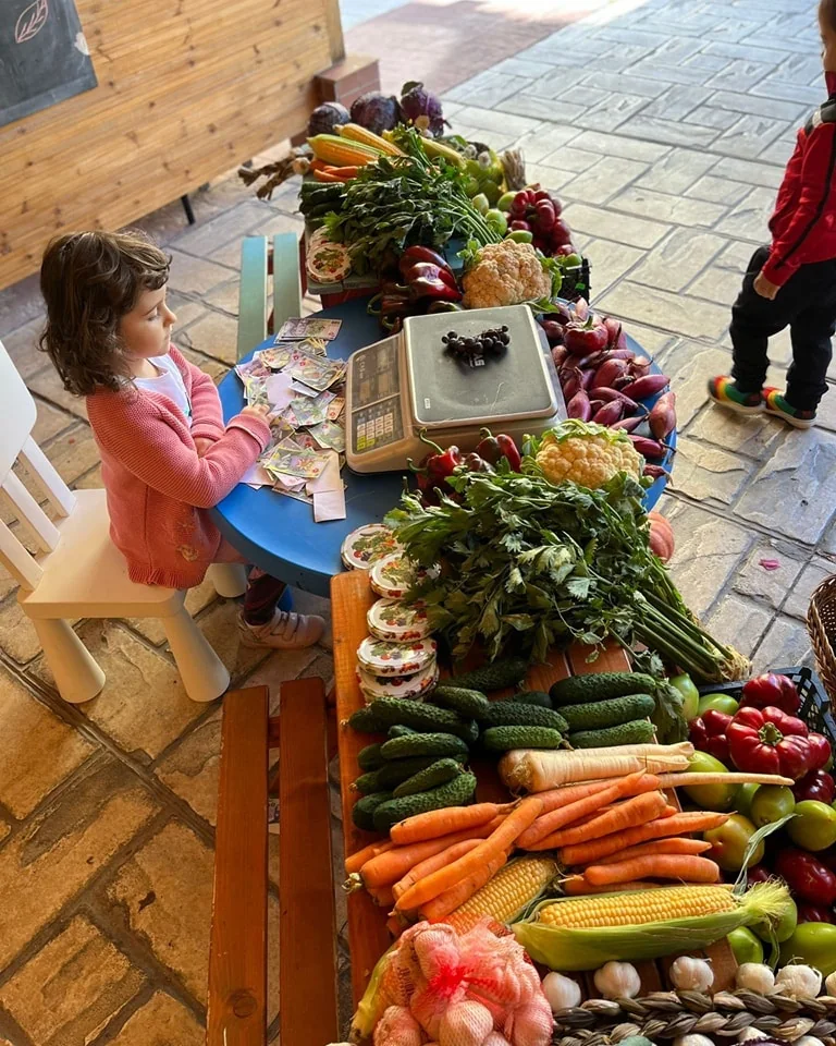 Copil la o masă cu legume și un cântar, la grădinița Fata din Dafin