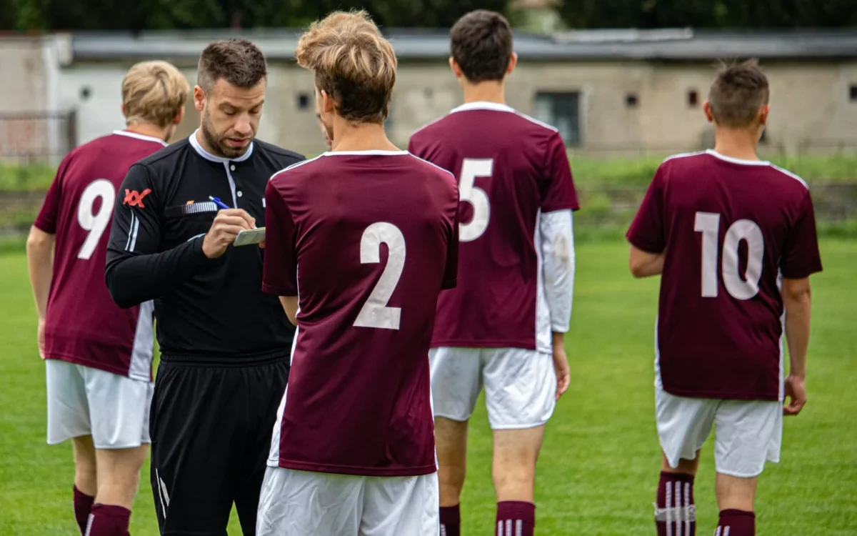 Arbitru de fotbal notează pe teren lângă un jucător