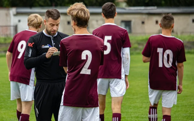 Arbitru de fotbal notează pe teren lângă un jucător