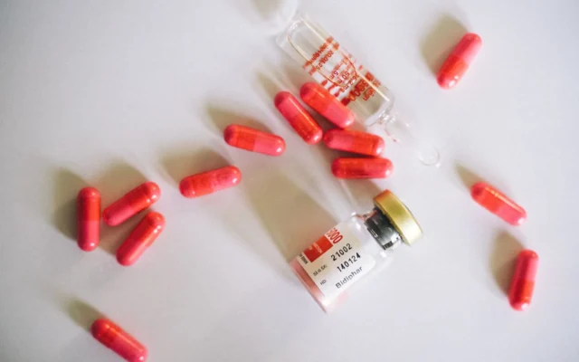 Capsule roșii și flacoane medicale pe fundal alb