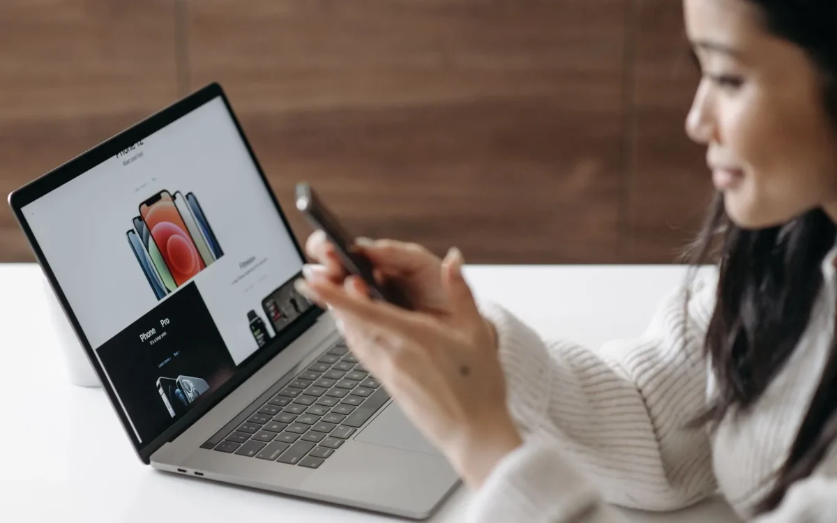 Persoană care folosește telefonul mobil lângă un laptop