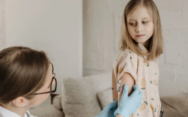 Cadru medical pregătind vaccinarea unui copil
