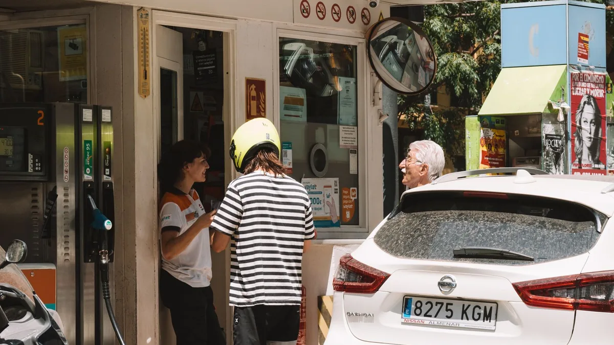 Persoane și autoturisme la o stație de alimentare
