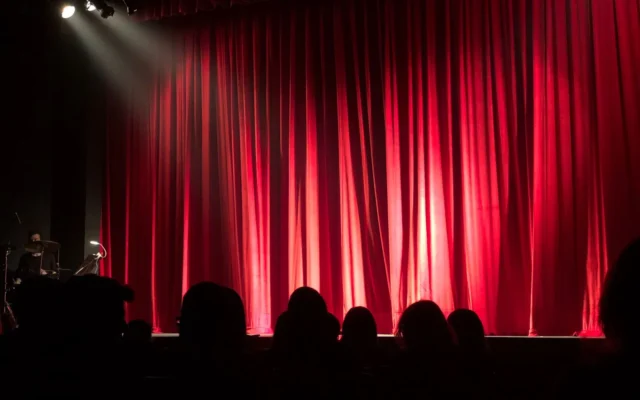 Scenă de teatru luminată și public în sală
