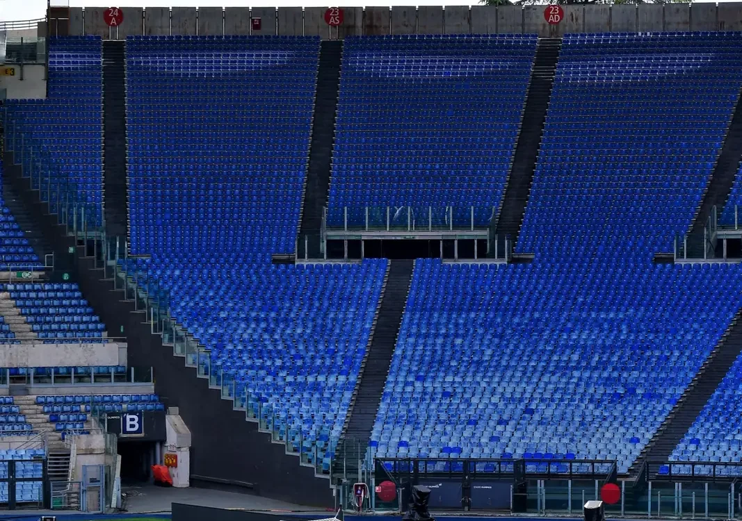 Teren de fotbal verde pe un stadion cu tribune goale