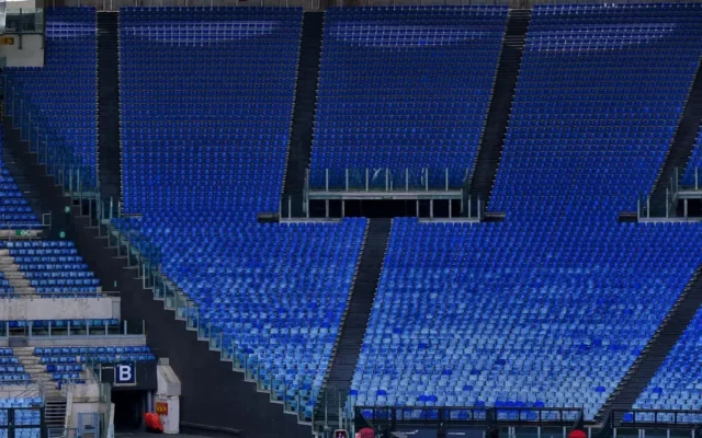 Teren de fotbal verde pe un stadion cu tribune goale