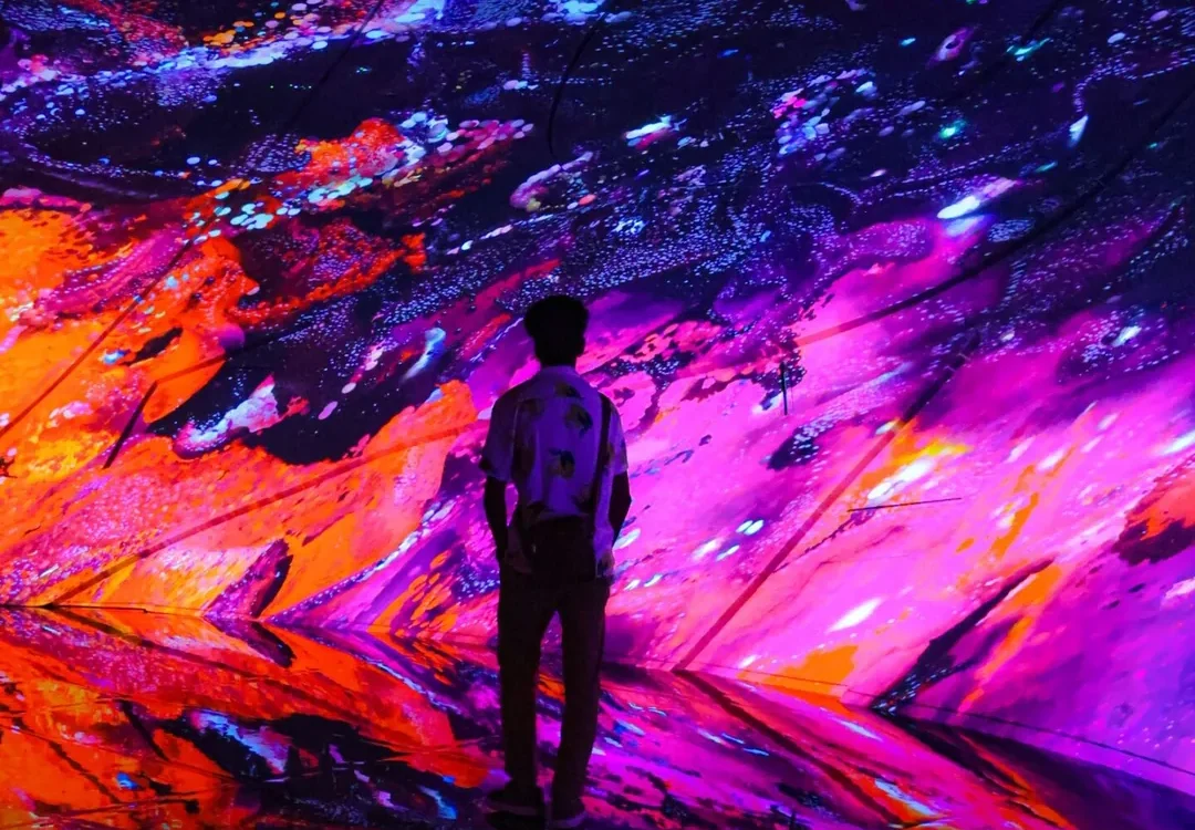 Vizitator în fața unor proiecții colorate de artă digitală