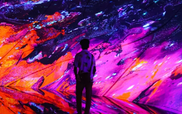 Vizitator în fața unor proiecții colorate de artă digitală
