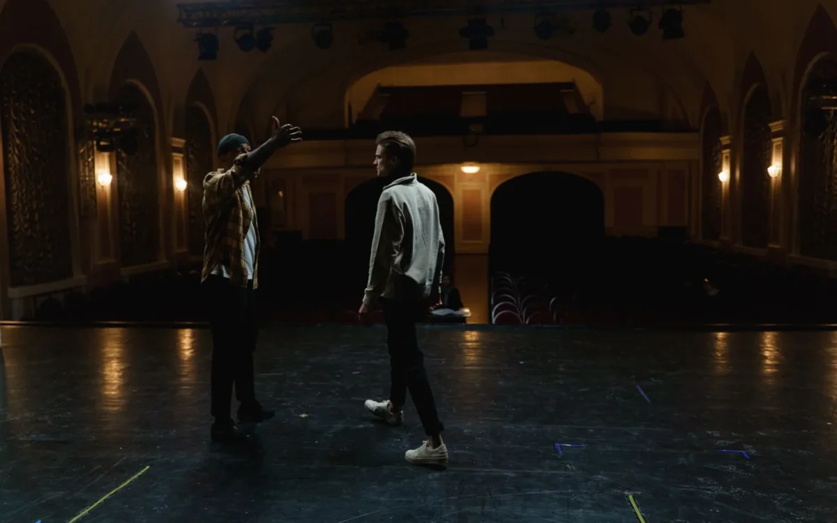 Doi actori pe scena unui teatru în timpul unei repetiții