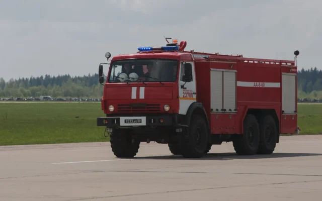 Autospecială roșie de pompieri pe o șosea lângă un câmp