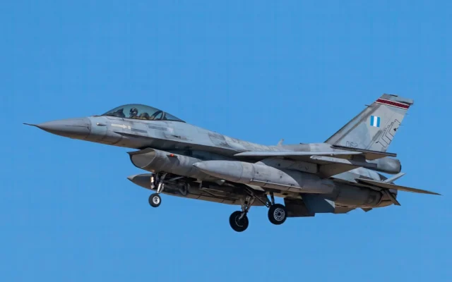 Avion F-16 în zbor pe cer albastru, cu trenul de aterizare coborât