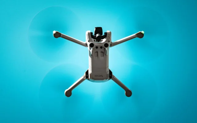 Dronă gri cu patru elice văzută de dedesubt în zbor