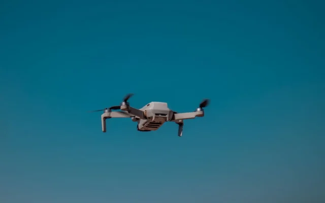 Dronă cu patru elice în zbor pe cer senin
