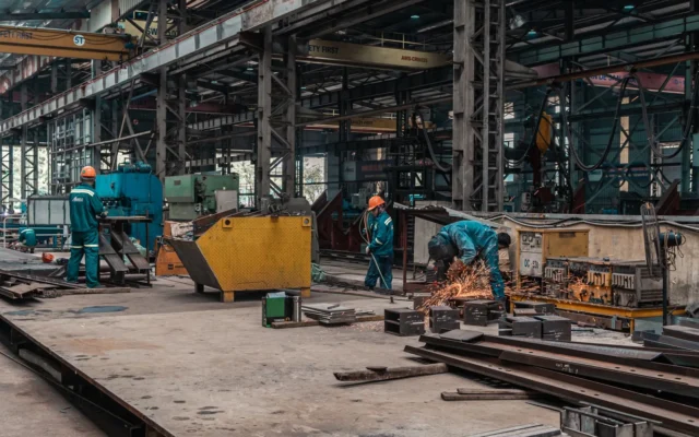 Lucrători într-un atelier cu echipamente pentru prelucrarea metalelor