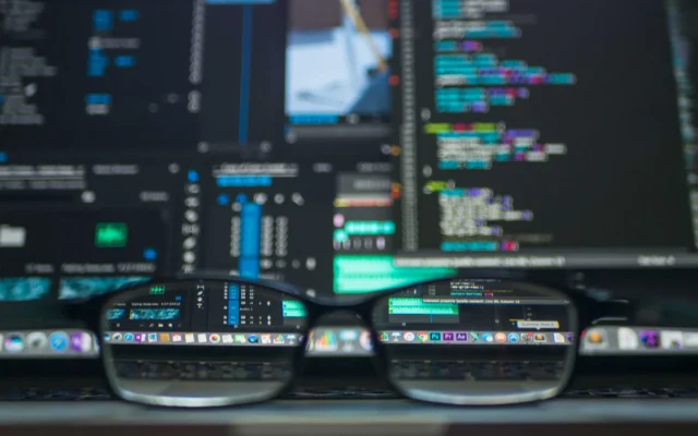 Ochelari în fața unui monitor cu cod de programare