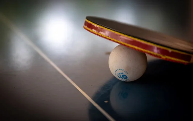 Paletă și minge de tenis de masă pe o masă neagră