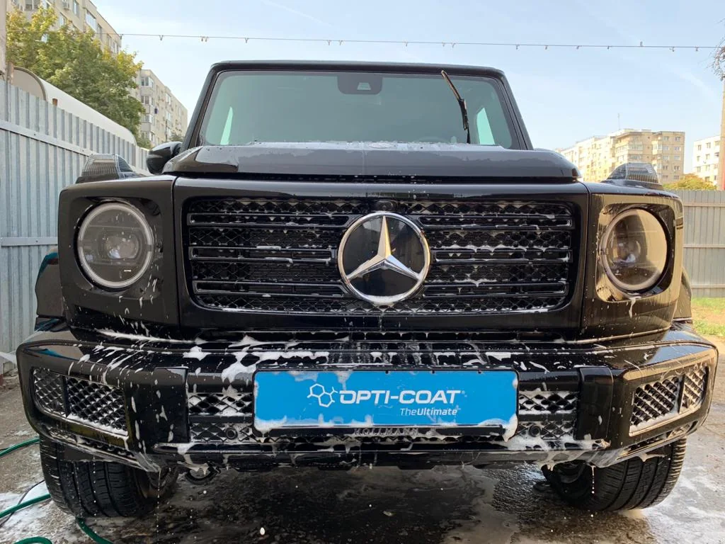 Un Mercedes-Benz Clasa G negru, acoperit parțial cu spumă în timpul spălării.